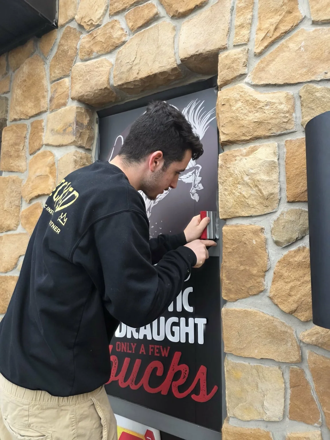 Wicked installer working on an exterior commercial graphic installation