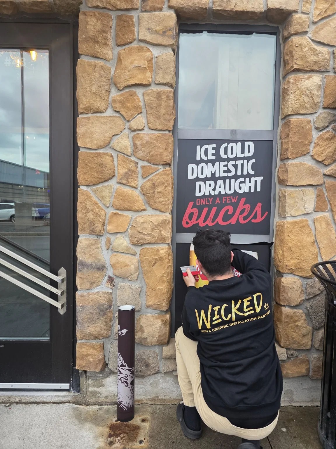 Wicked installer applying a commercial window graphic at Chuck's Roadhouse